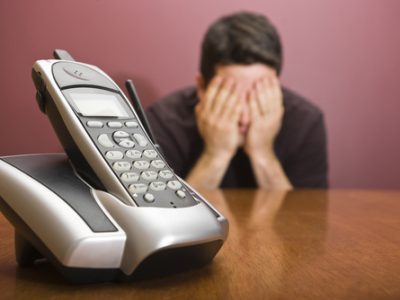 Man hides his face waiting for the phone to ring