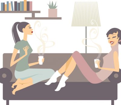 female friends with coffee cups talking at home