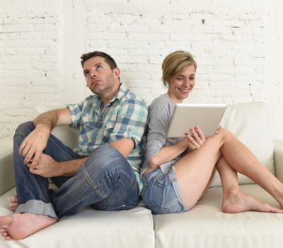 attractive couple at home couch happy woman internet addict on digital tablet ignoring sad husband