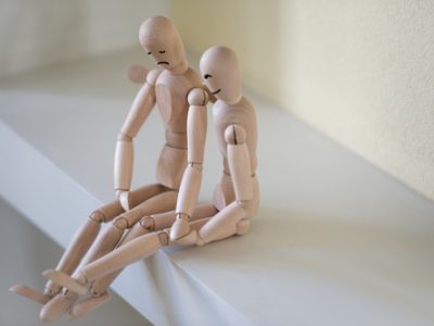 Wooden people sitting at home and supporting each other. People