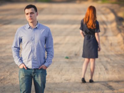 sad man and woman stand on the dirt road